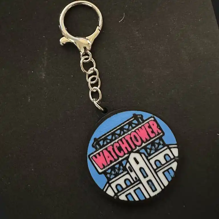 A round 3D-printed Watchtower sign design with a metal keychain clasp and chain attached